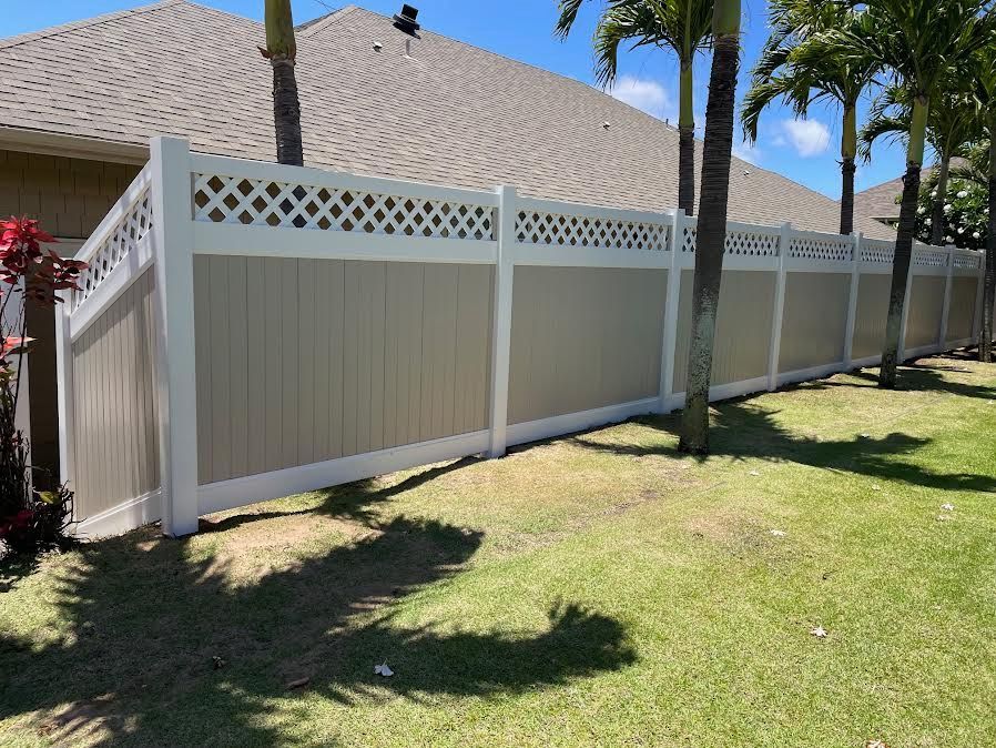 A white fence is surrounded by palm trees in front of a house.