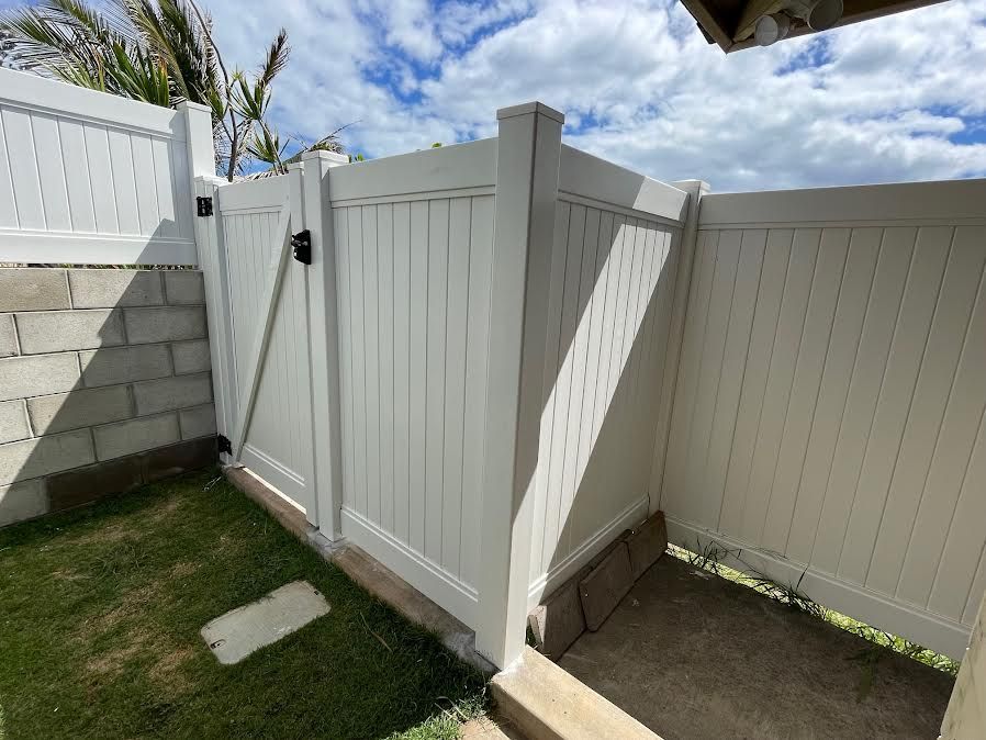 A white fence with a gate in the backyard of a house.
