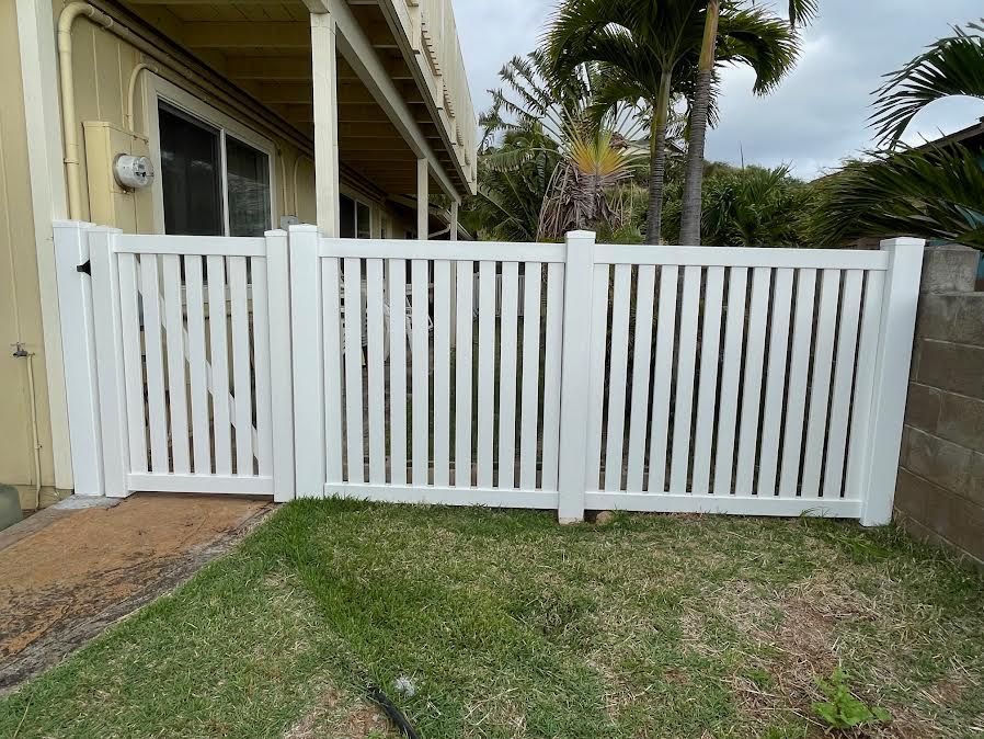 A white fence with a gate in front of a house.