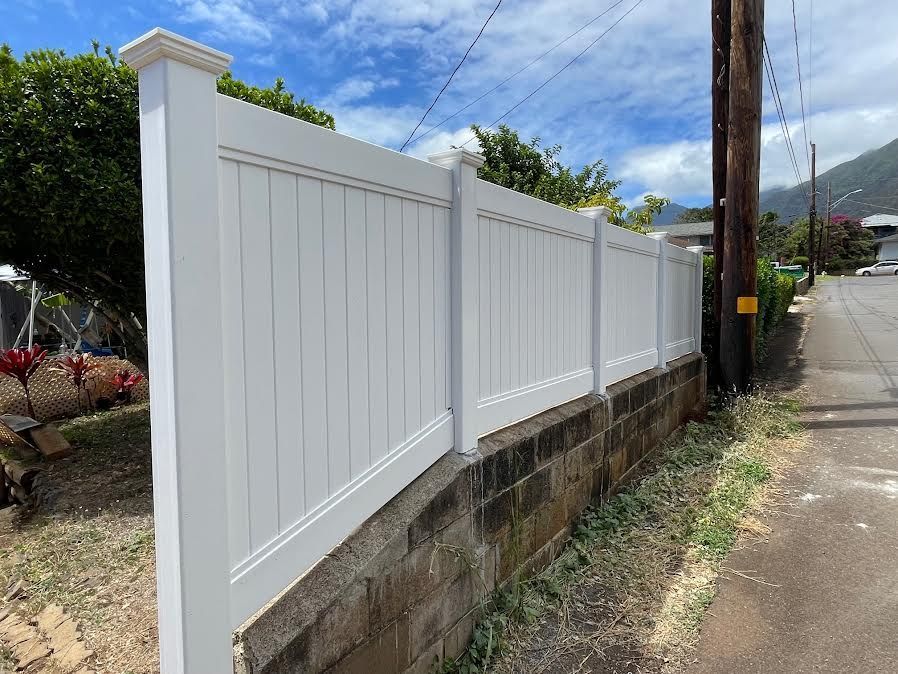 A white fence is sitting next to a brick wall.