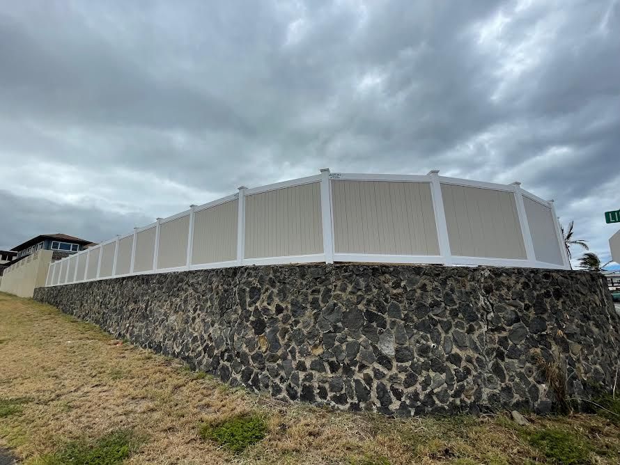 A white fence is sitting on top of a stone wall.