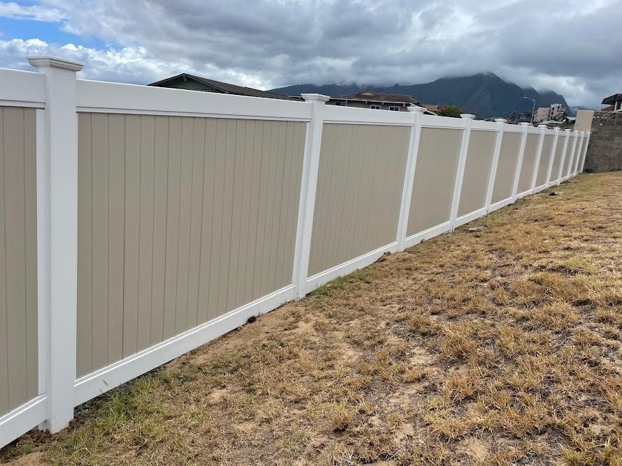 A white and tan fence is sitting in the middle of a grassy field.