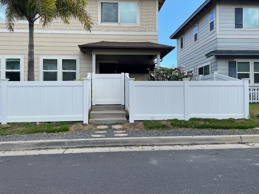 A white fence is in front of a house.