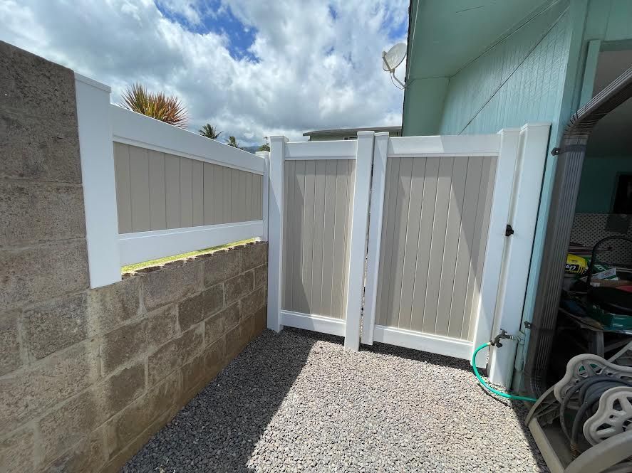 A white fence is sitting next to a brick wall.