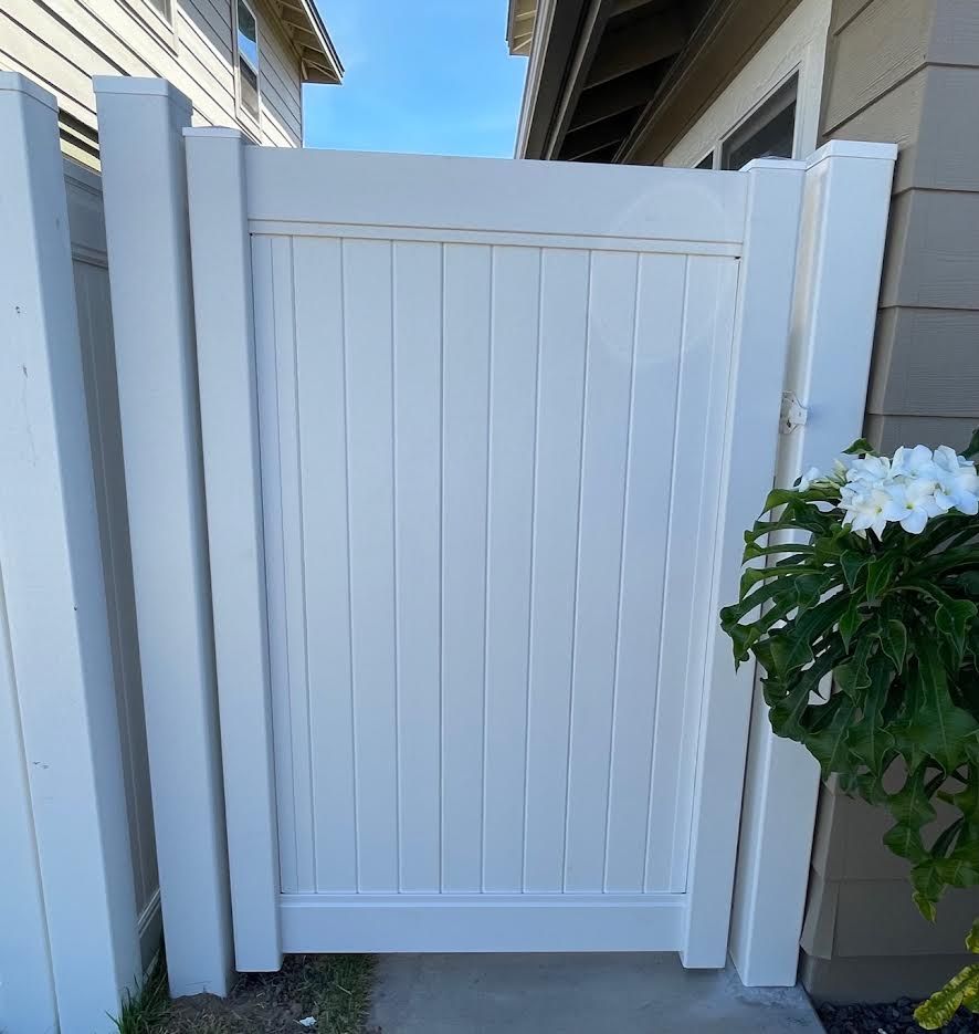 A white fence with a gate in front of a house