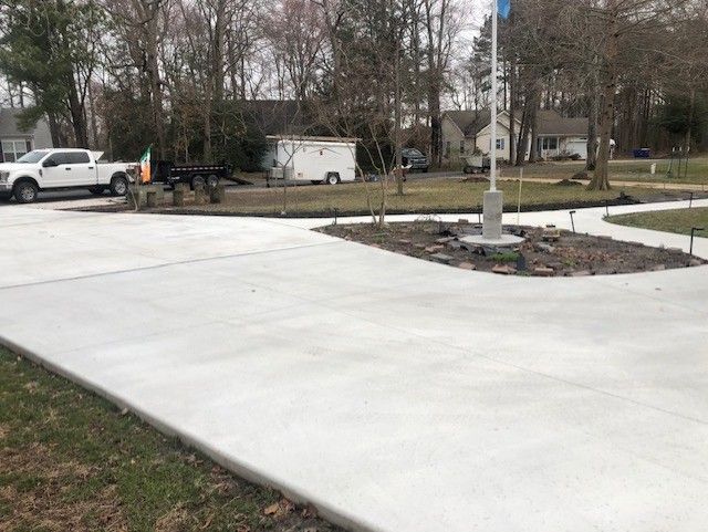 A concrete driveway with a flag pole in the middle of it.