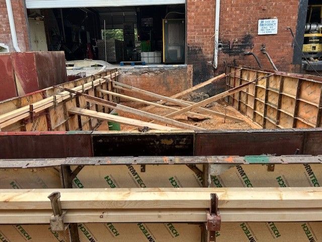 A large wooden structure is being built in front of a brick building.