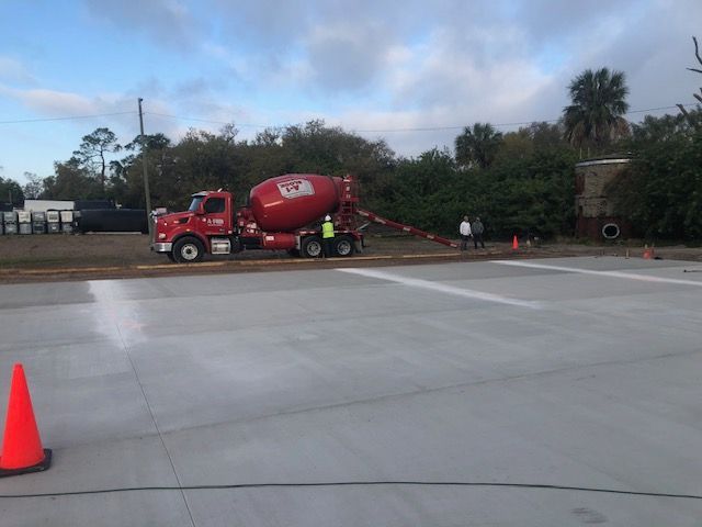 A red concrete mixer truck is driving down a concrete road.