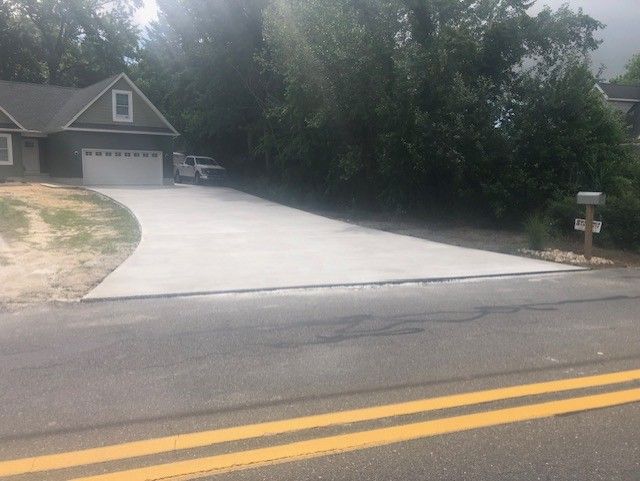 There is a concrete driveway leading to a house.