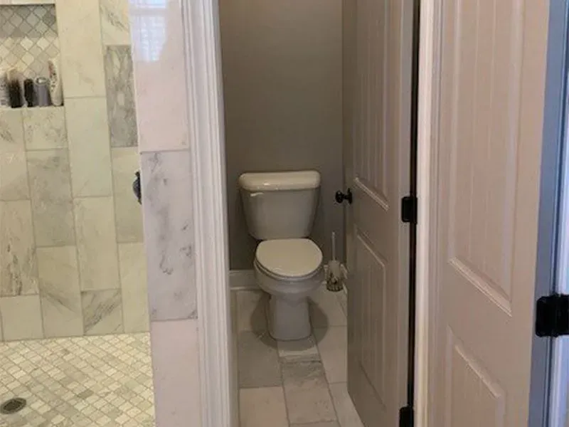 Bathroom: toilet between two white doors, shower on the left.