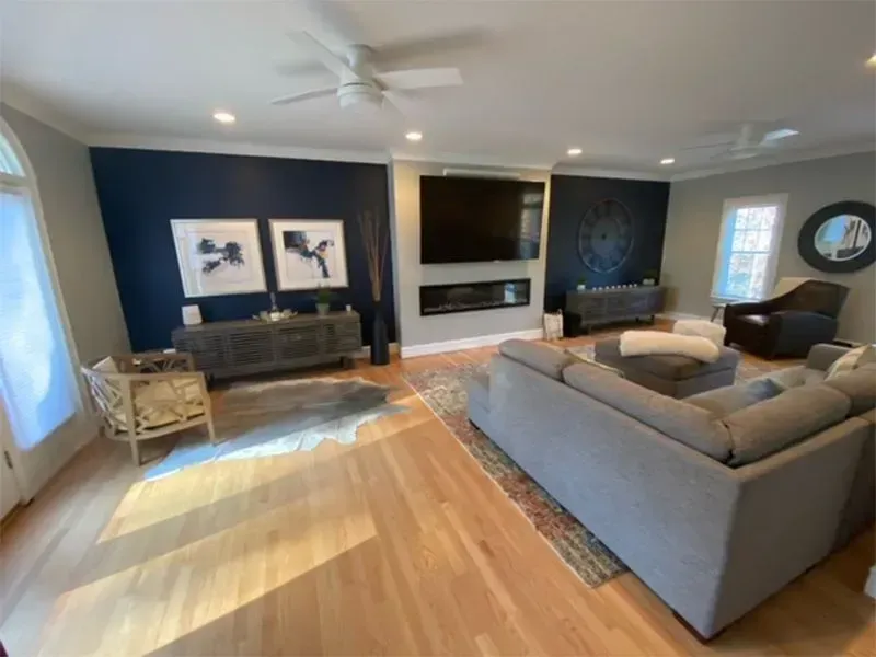 Spacious living room with hardwood floors, navy accent walls, a fireplace, and a large gray sectional sofa.