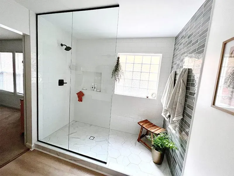Modern bathroom with glass shower, hexagonal tile floor, and accent wall with gray tiles.