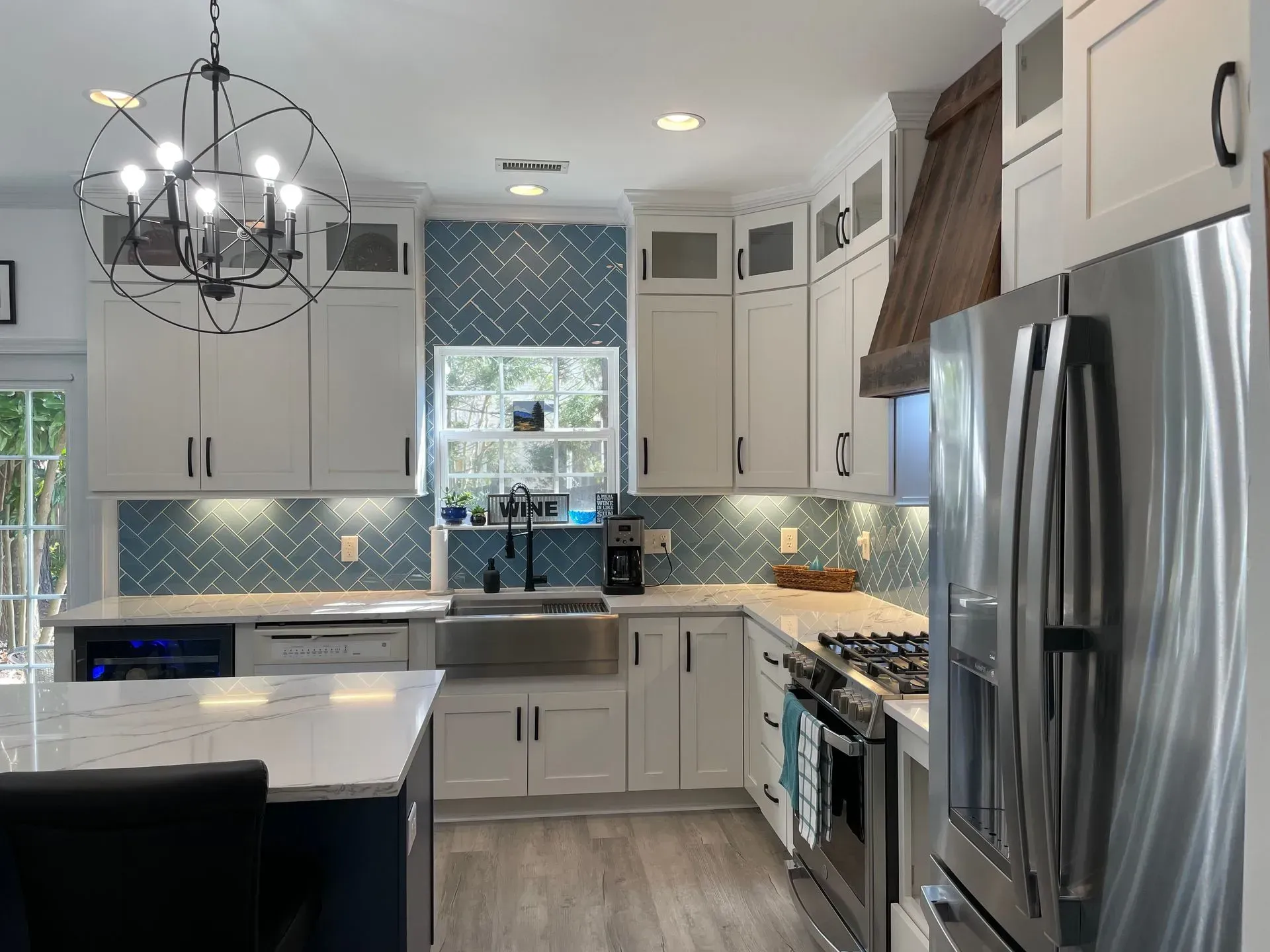Kitchen with white cabinets, blue tile backsplash, stainless steel appliances, and a dark island.