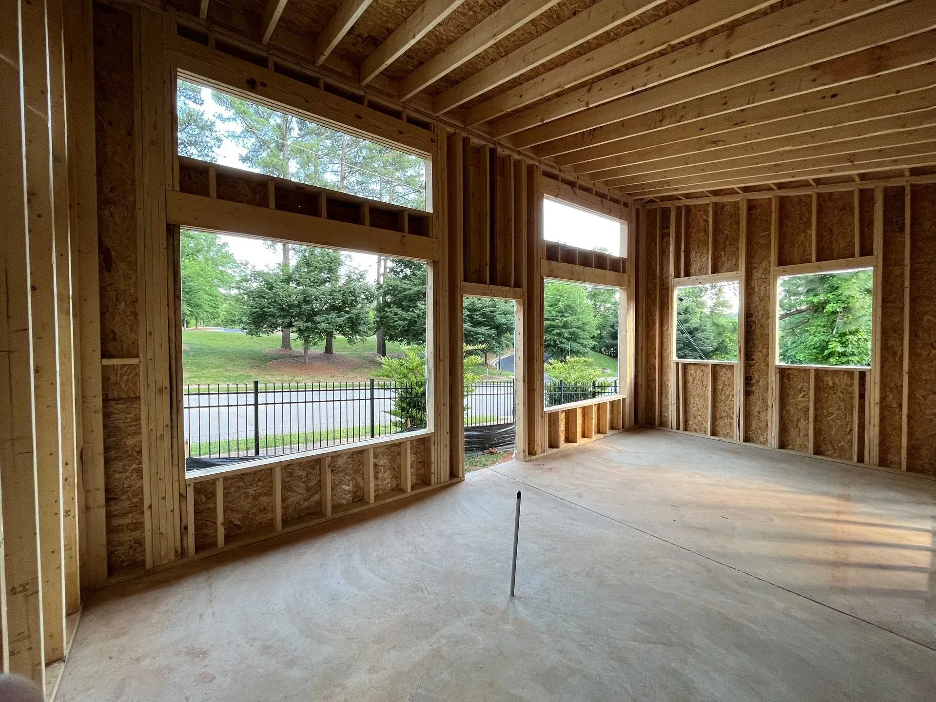 Interior view of a building under construction, showing wooden framing for walls, windows, and ceiling; exterior view through the window.