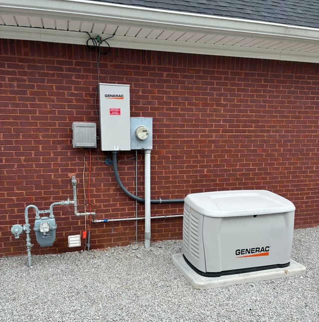 Gas meter and electrical equipment mounted on a red brick wall beside a white Generac generator.