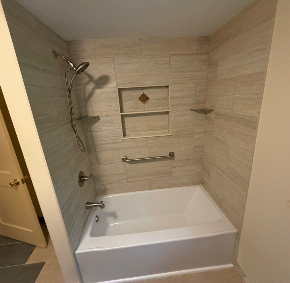 Accessible bathroom with beige tiled shower-tub combo, built-in shelf, grab bars, and showerhead.