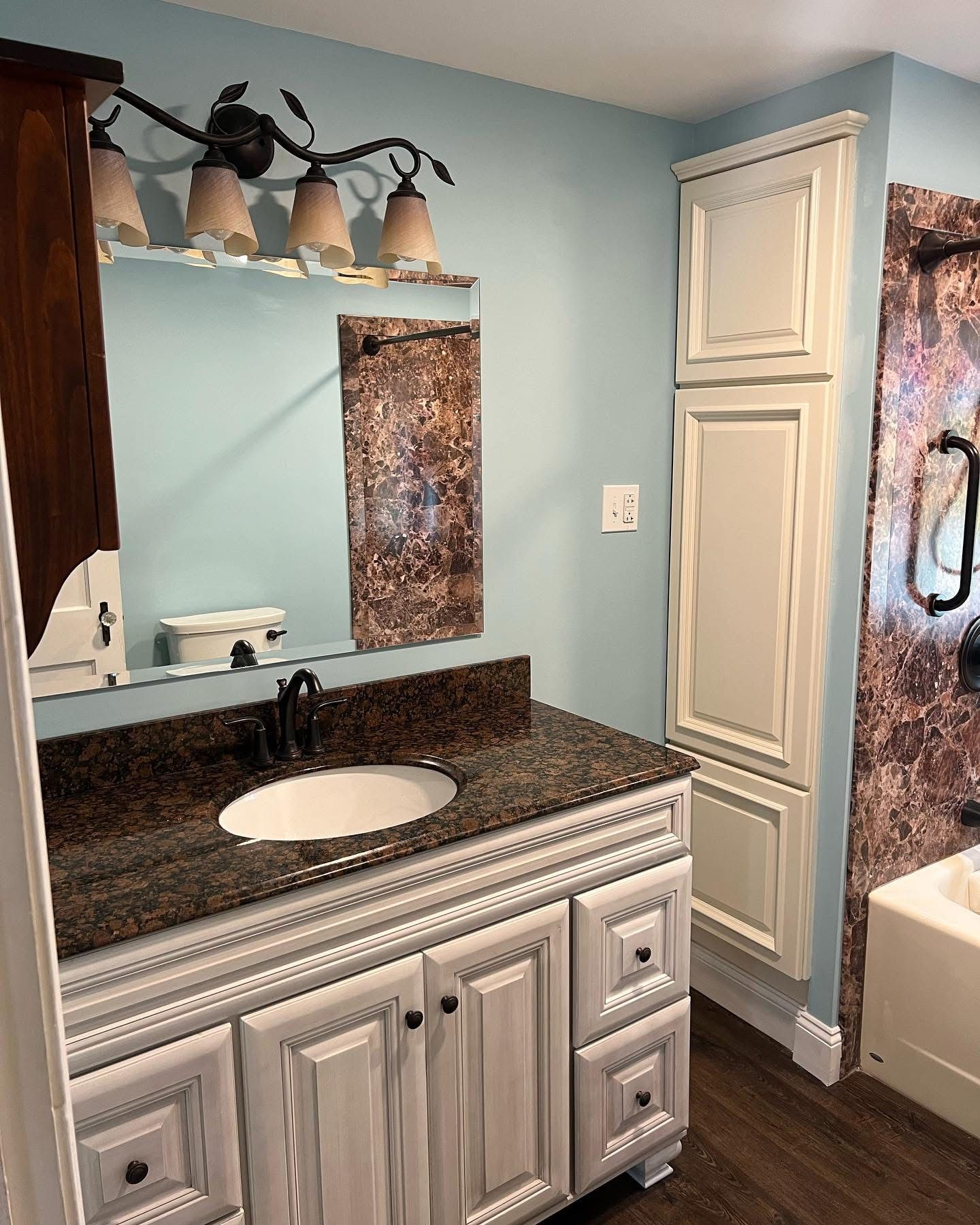 A bathroom with a sink , mirror , cabinets and a bathtub.