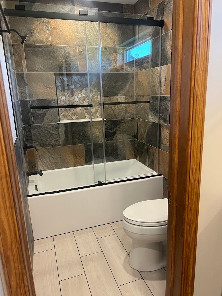 A bathroom with a toilet , tub and shower.