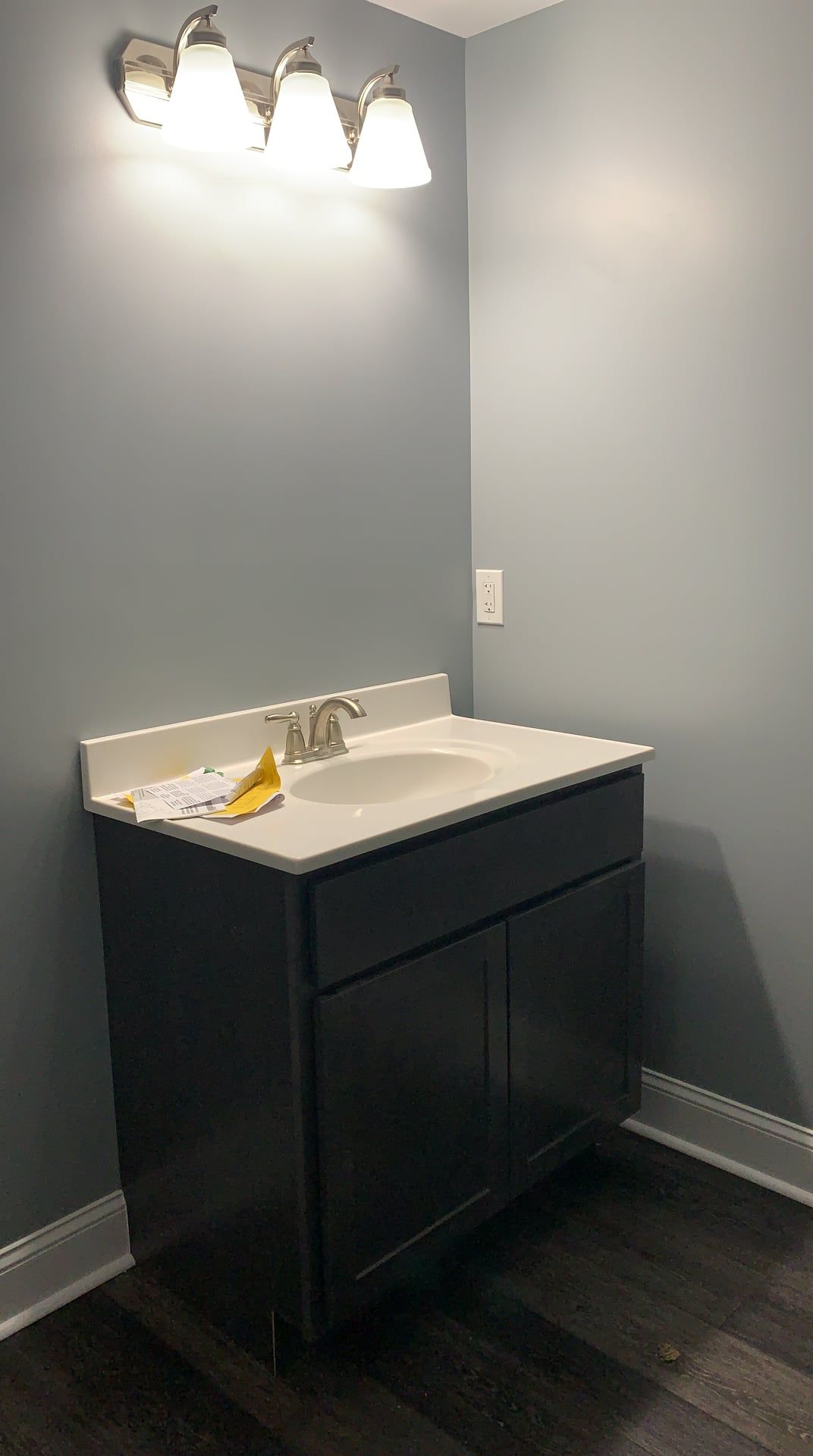 A bathroom with a sink and a light fixture on the wall.