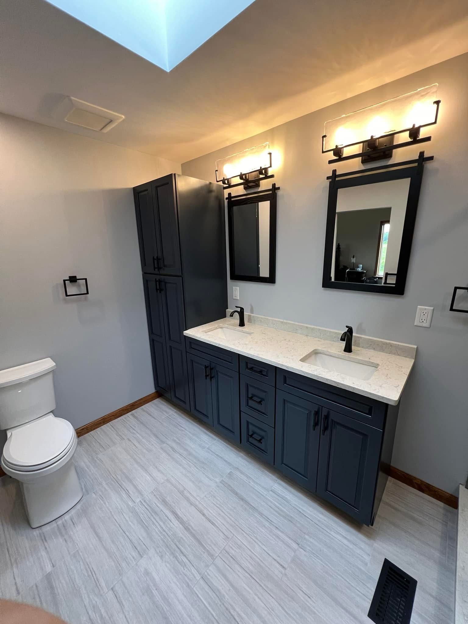 A bathroom with two sinks , a toilet , and a skylight.