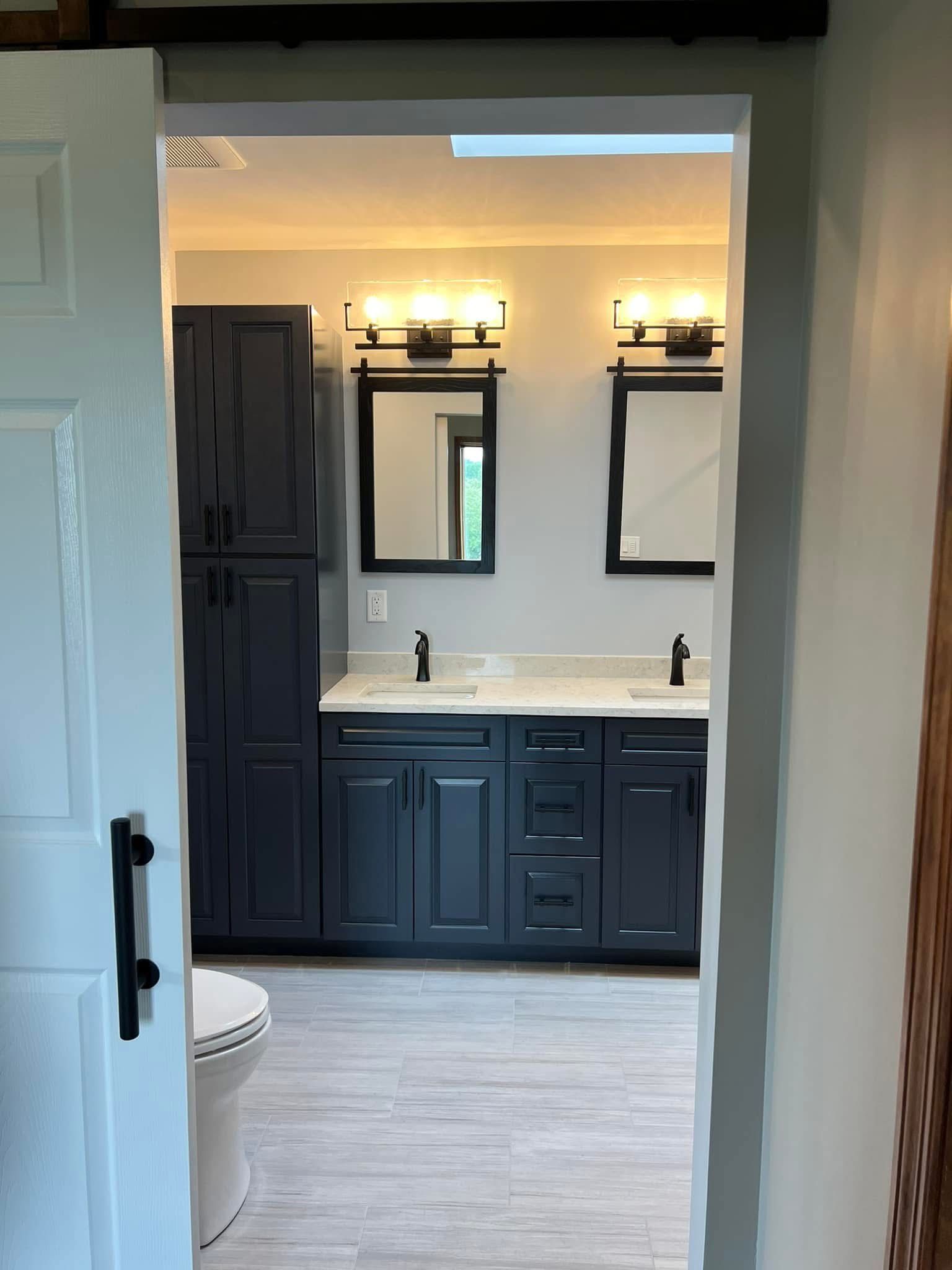 A bathroom with two sinks , two mirrors and a toilet.