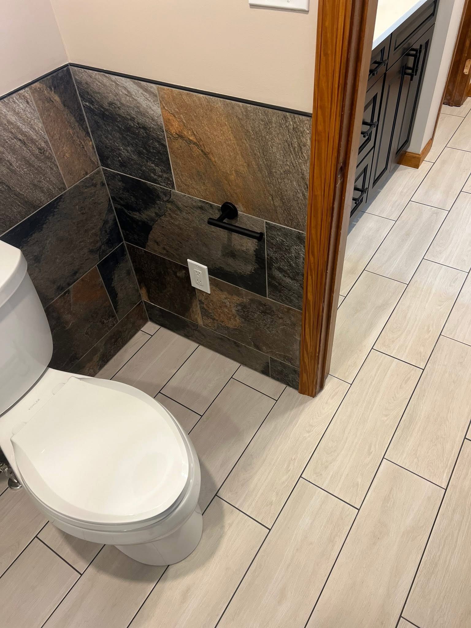 A bathroom with a toilet , sink , and tile floor.