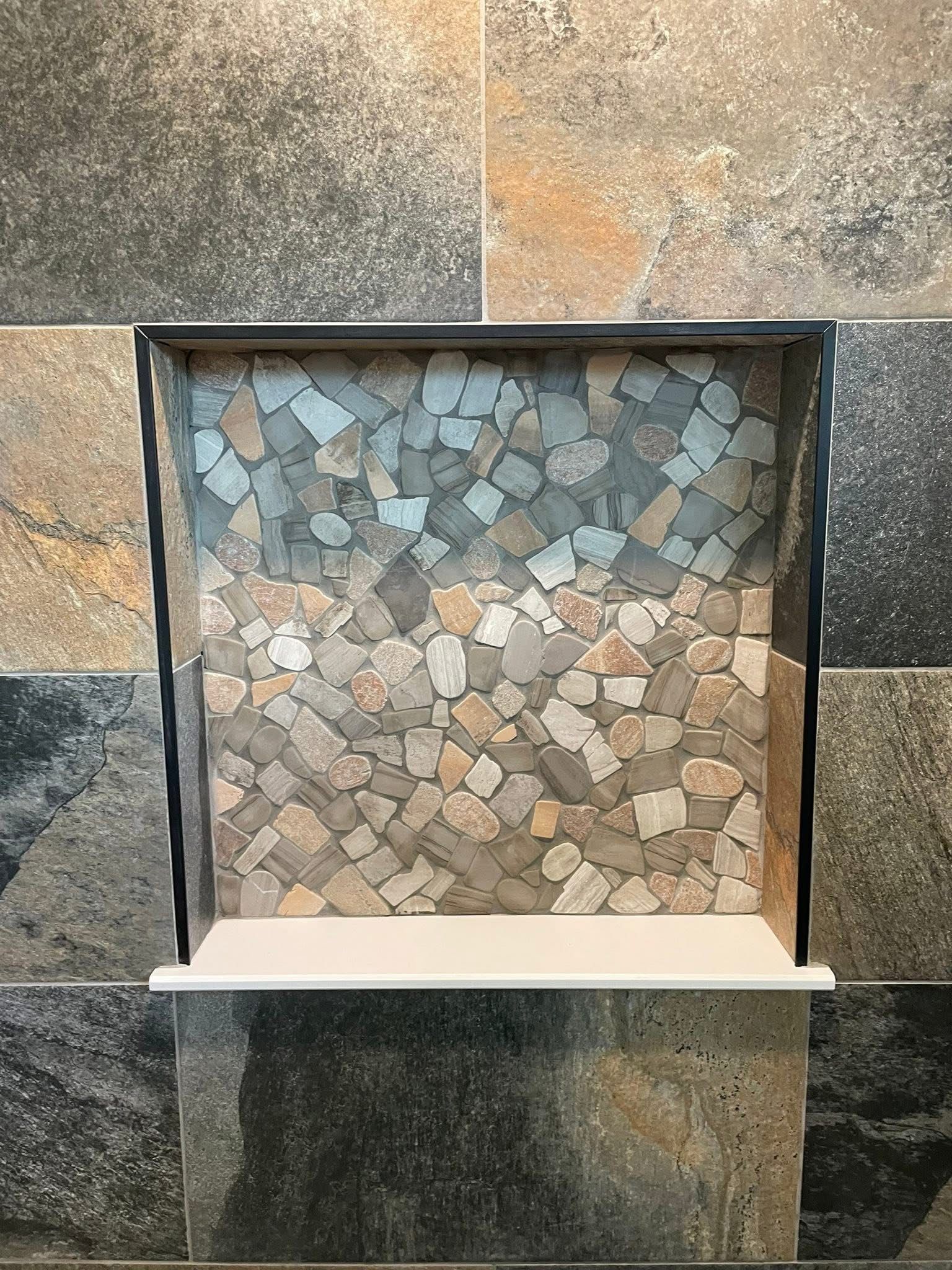 A shower niche with a mosaic tile wall and a shelf.