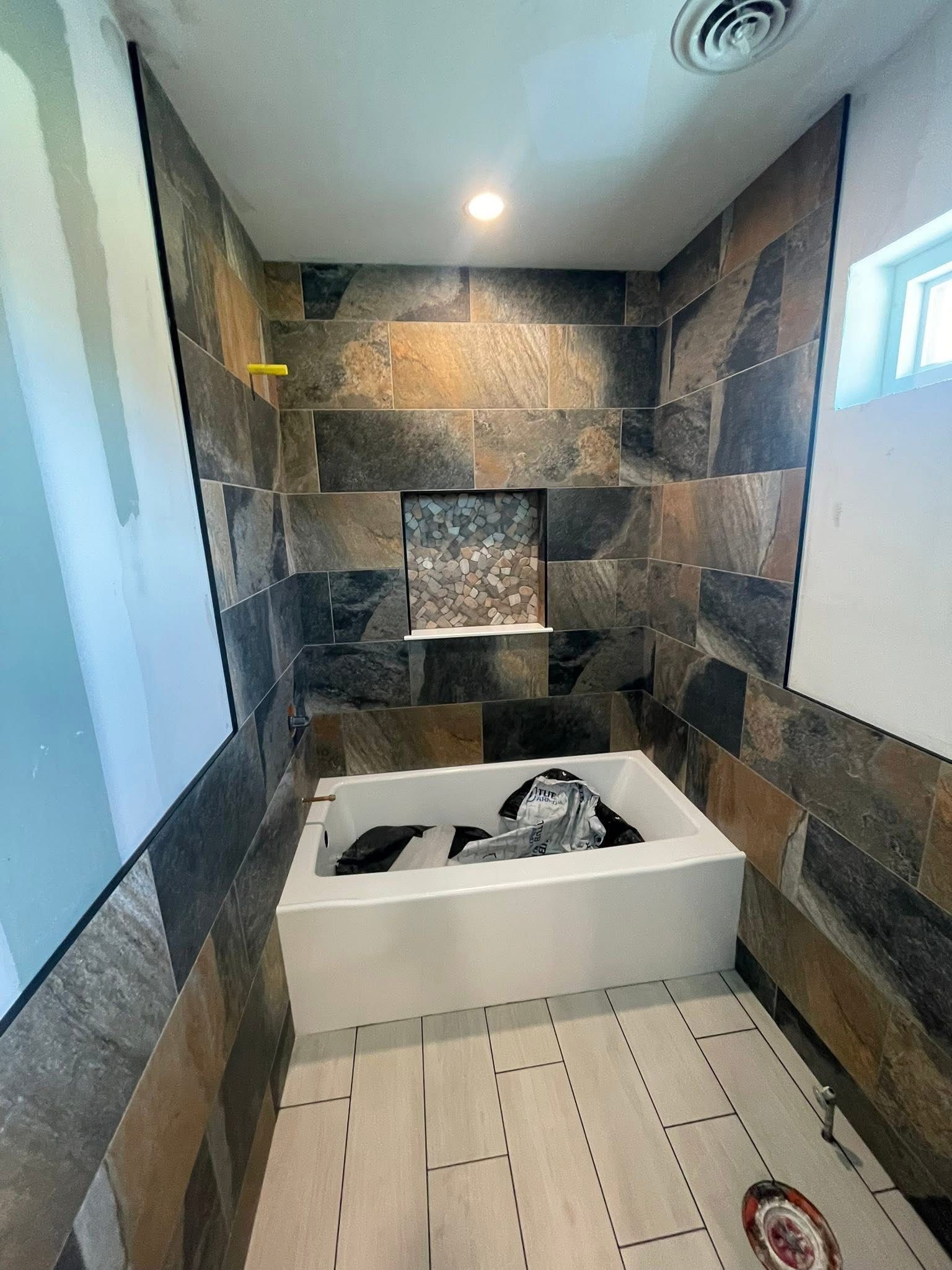 A bathroom with a bathtub and tiled walls.