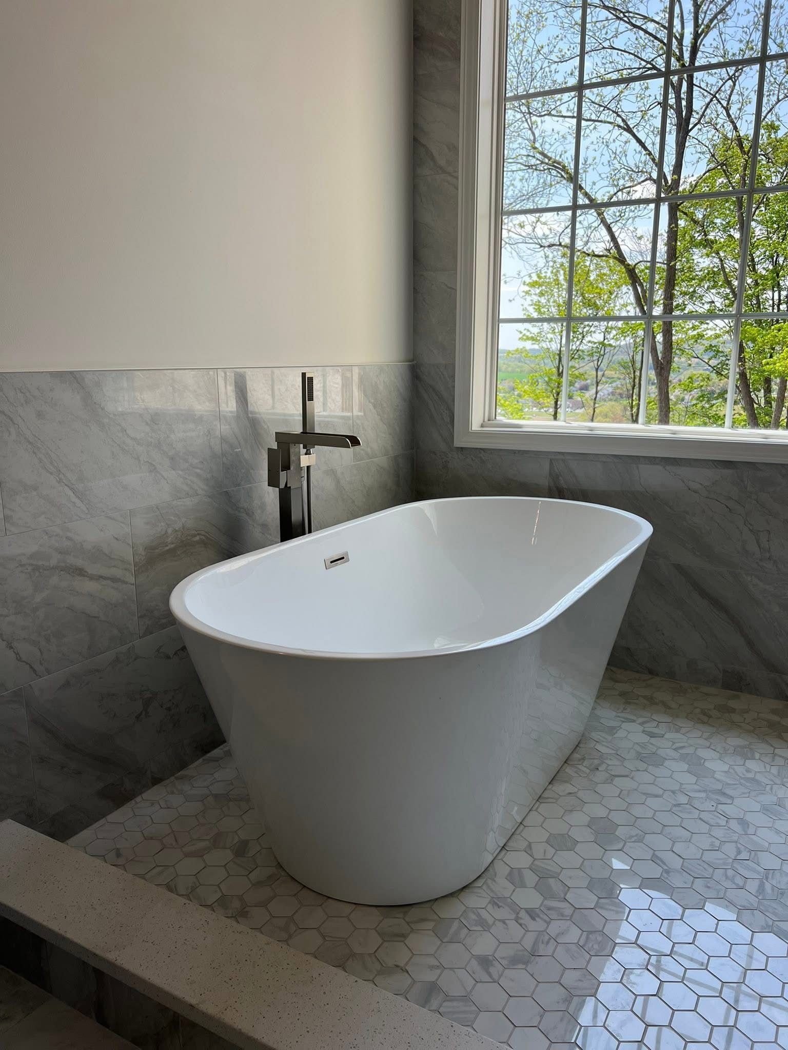 A white bathtub is sitting in a bathroom next to a window.