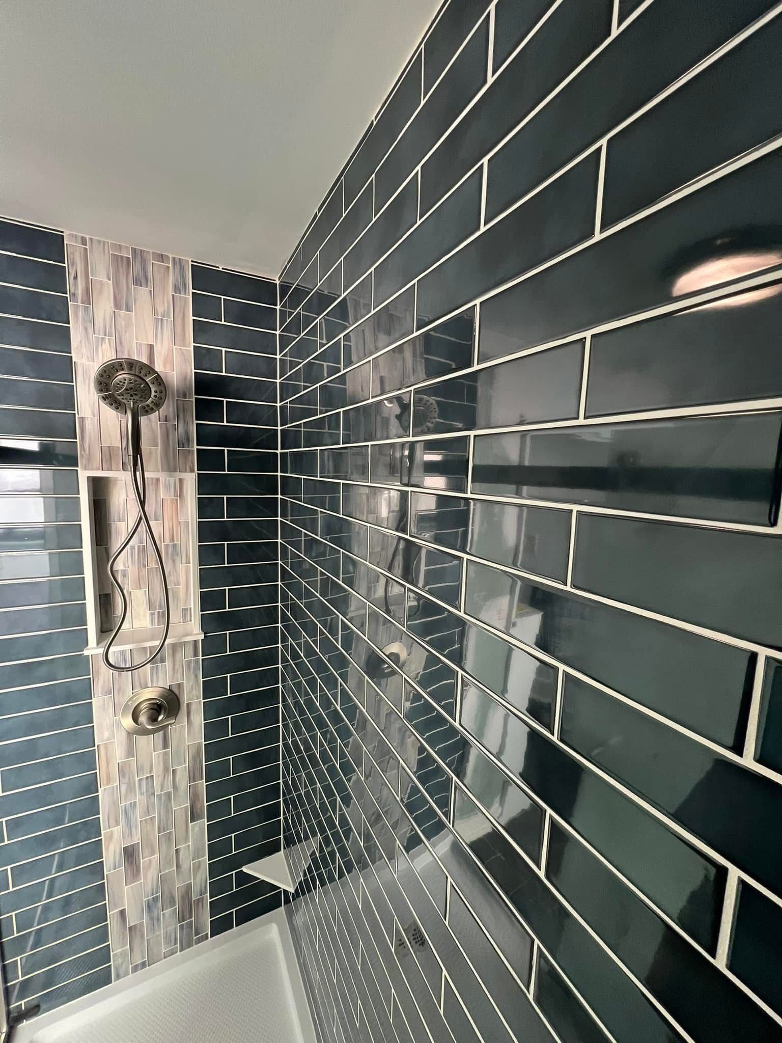 A bathroom with black tiles and a shower head.