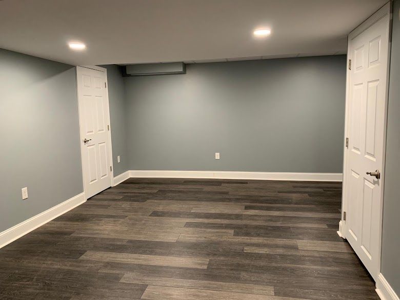 Empty room with gray walls, dark wood-look flooring.