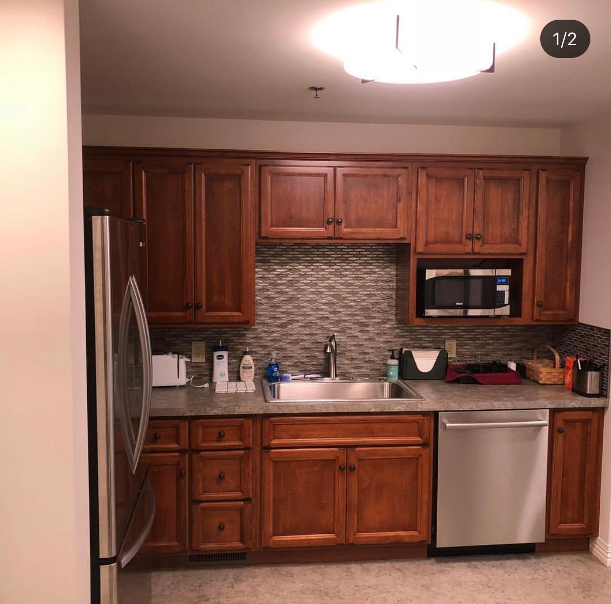 Kitchen with brown cabinets, stainless steel appliances, and gray backsplash.