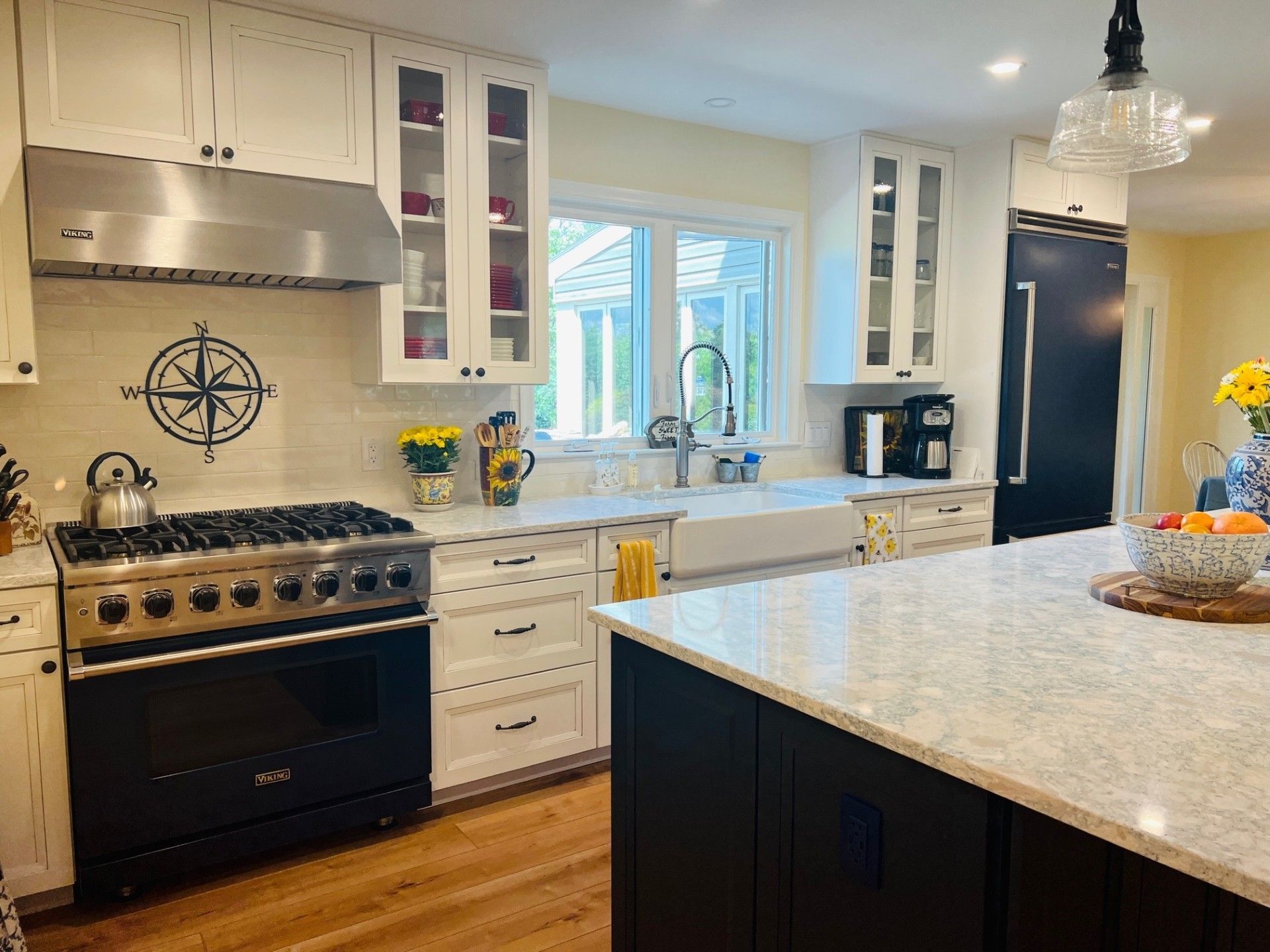A modern kitchen with white cabinets, stainless steel appliances, and a black island with a quartz countertop.