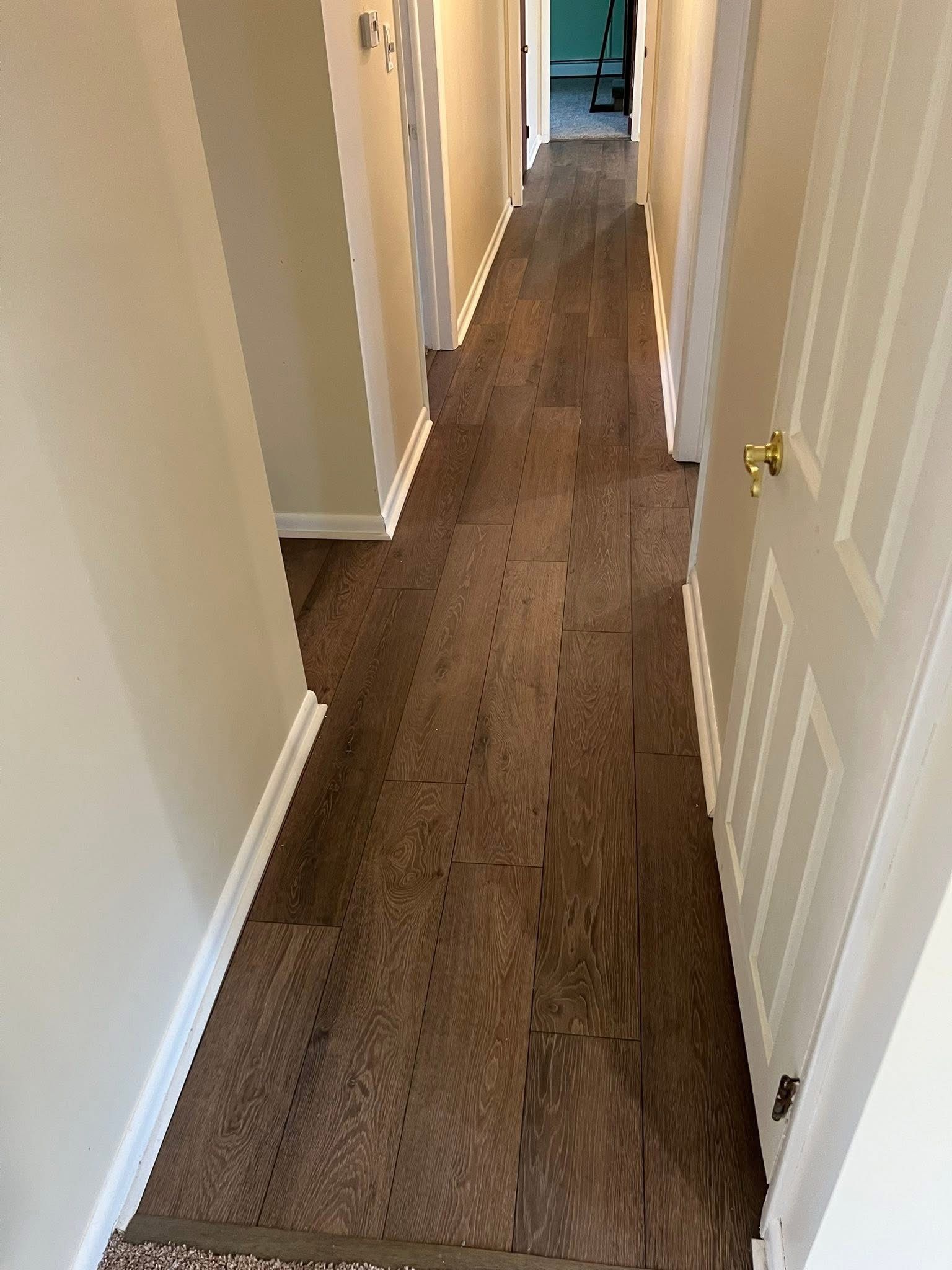A long hallway with a wooden floor and white doors.
