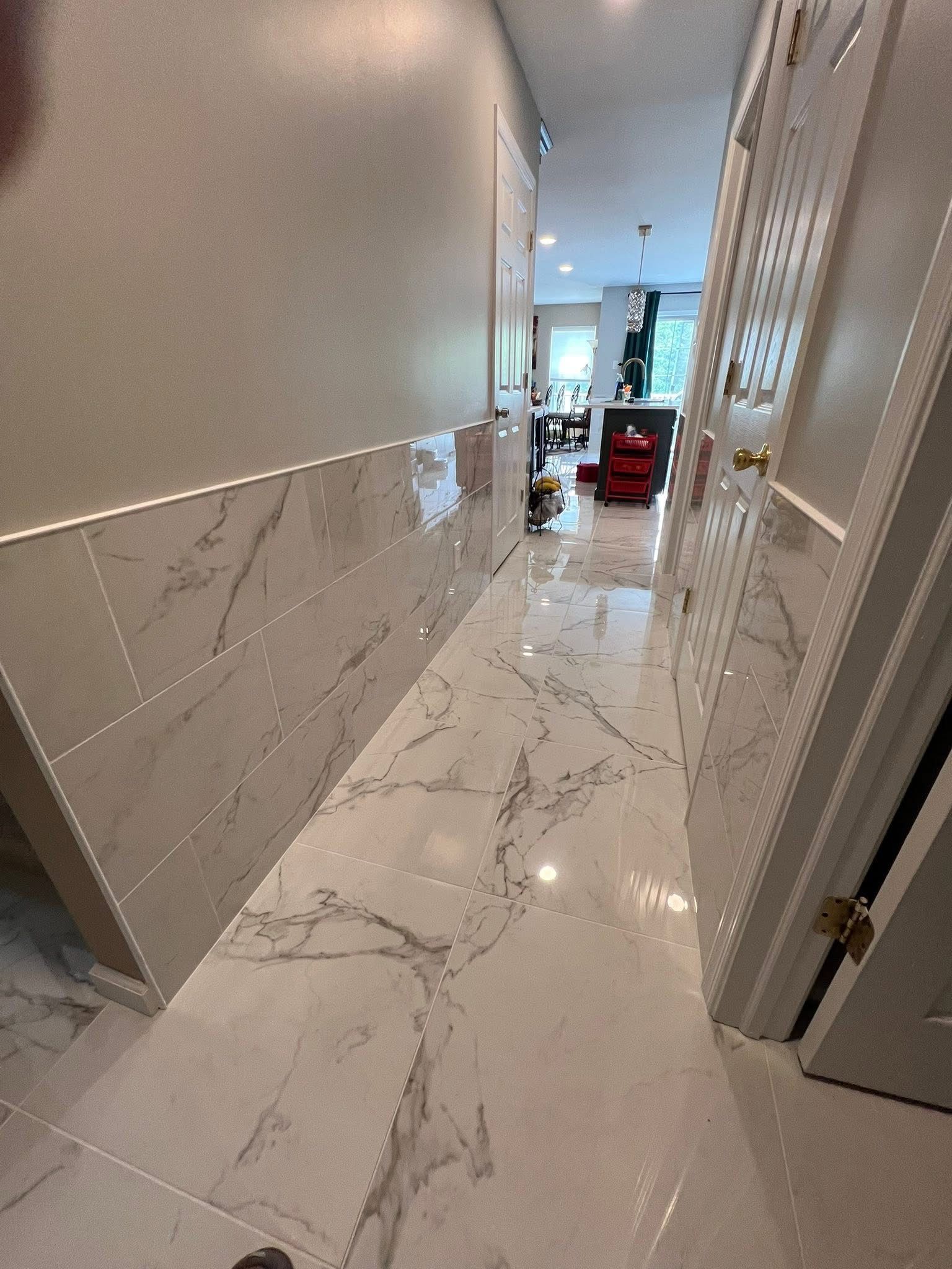 A hallway with white tiles and marble floors leading to a living room.
