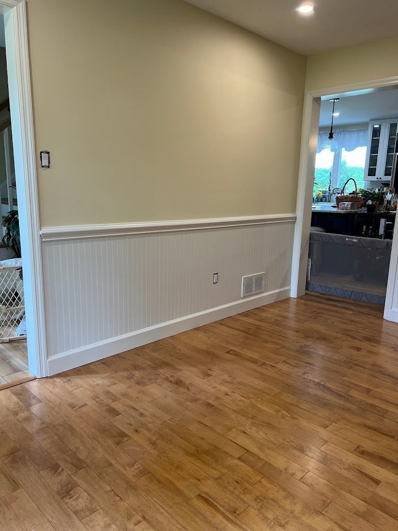 A living room with hardwood floors and white wainscoting.