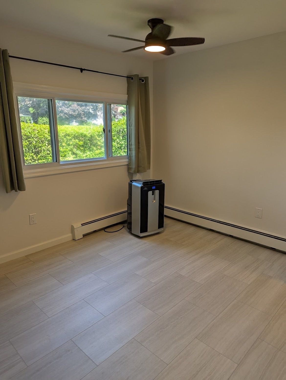 An empty room with a ceiling fan and a window.