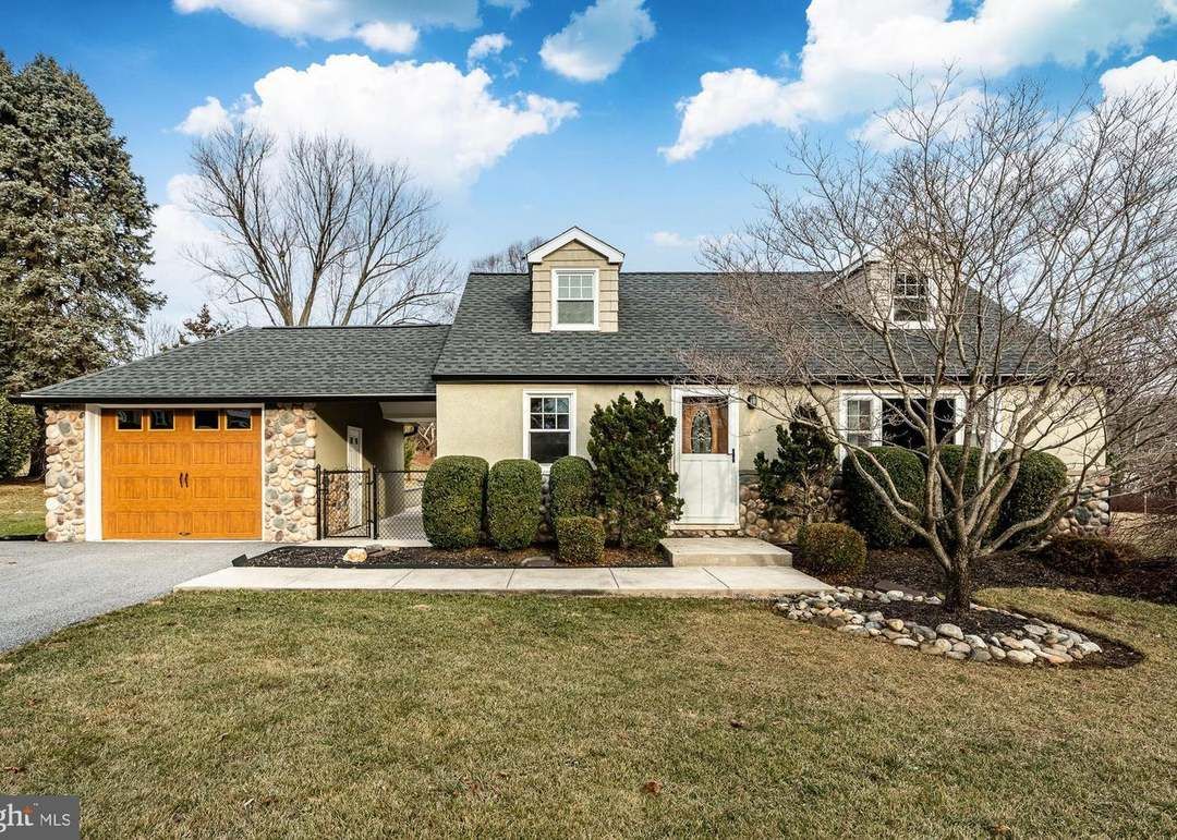 Tan ranch home with brown garage door, front lawn, and cloudy sky.