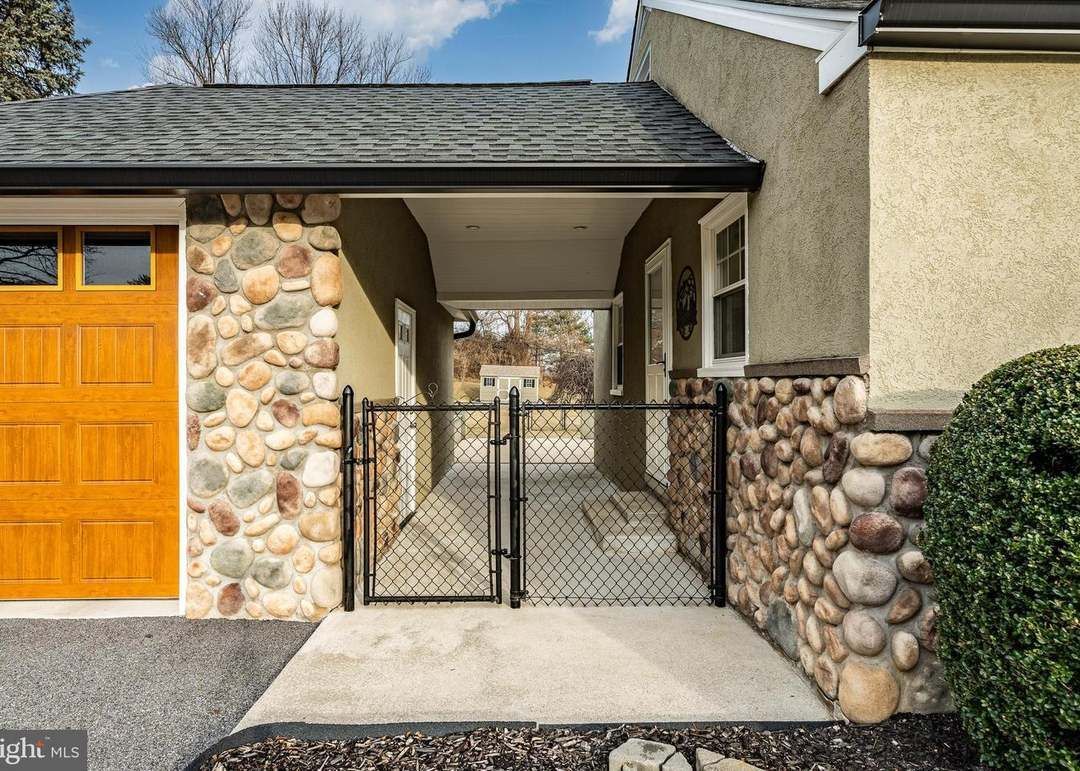 House exterior with stone accents, covered entry, black gate, and a garage door.