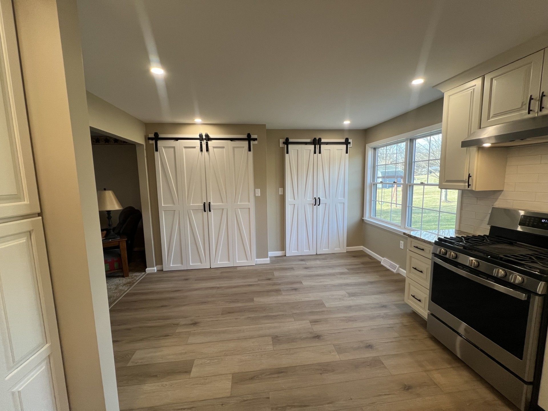 Kitchen with white barn doors, stainless steel appliances, and wood-look flooring. 