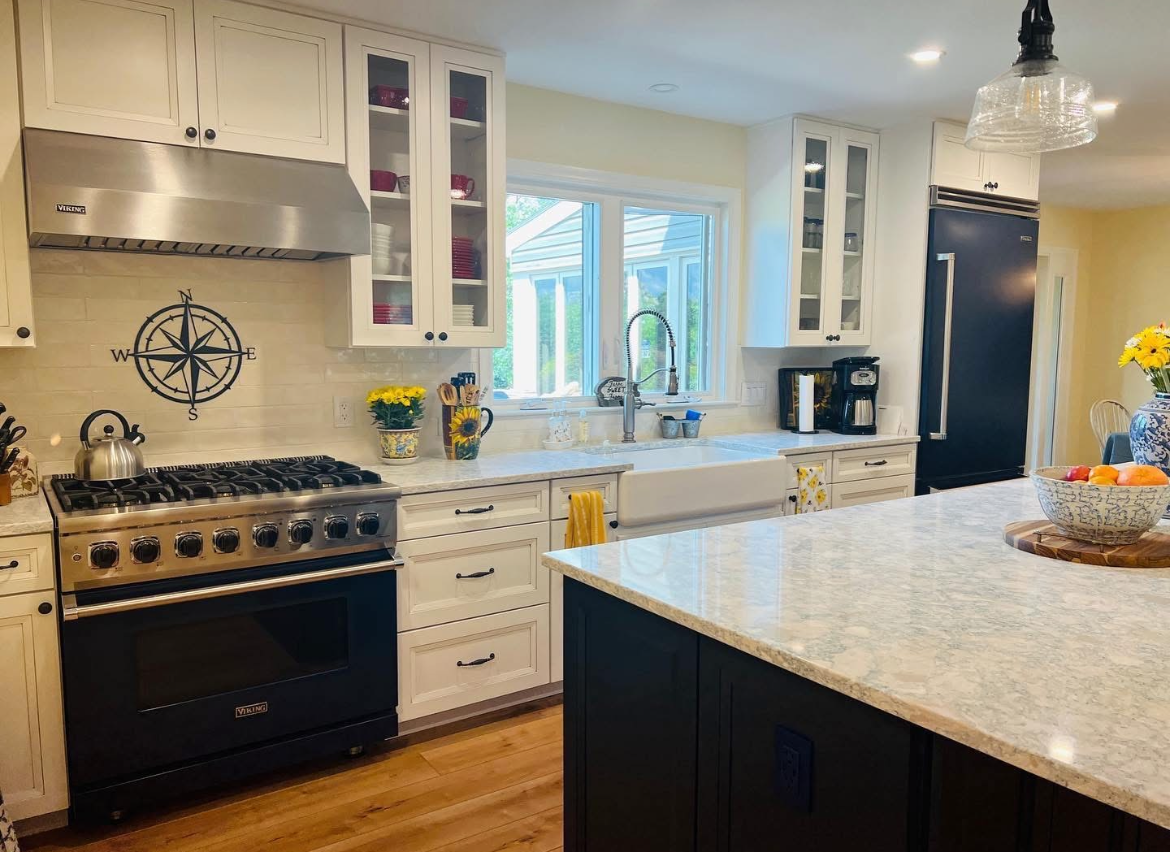 A kitchen with a stove , refrigerator , sink , and compass on the wall.