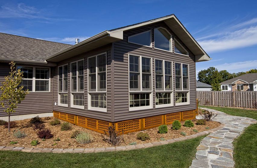 A house with a walkway leading to it and a sunroom with a lot of windows.