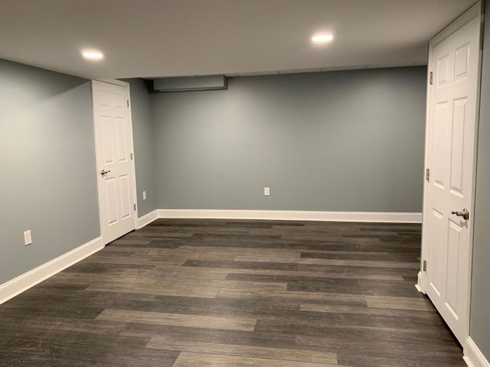 An empty basement with hardwood floors and blue walls.