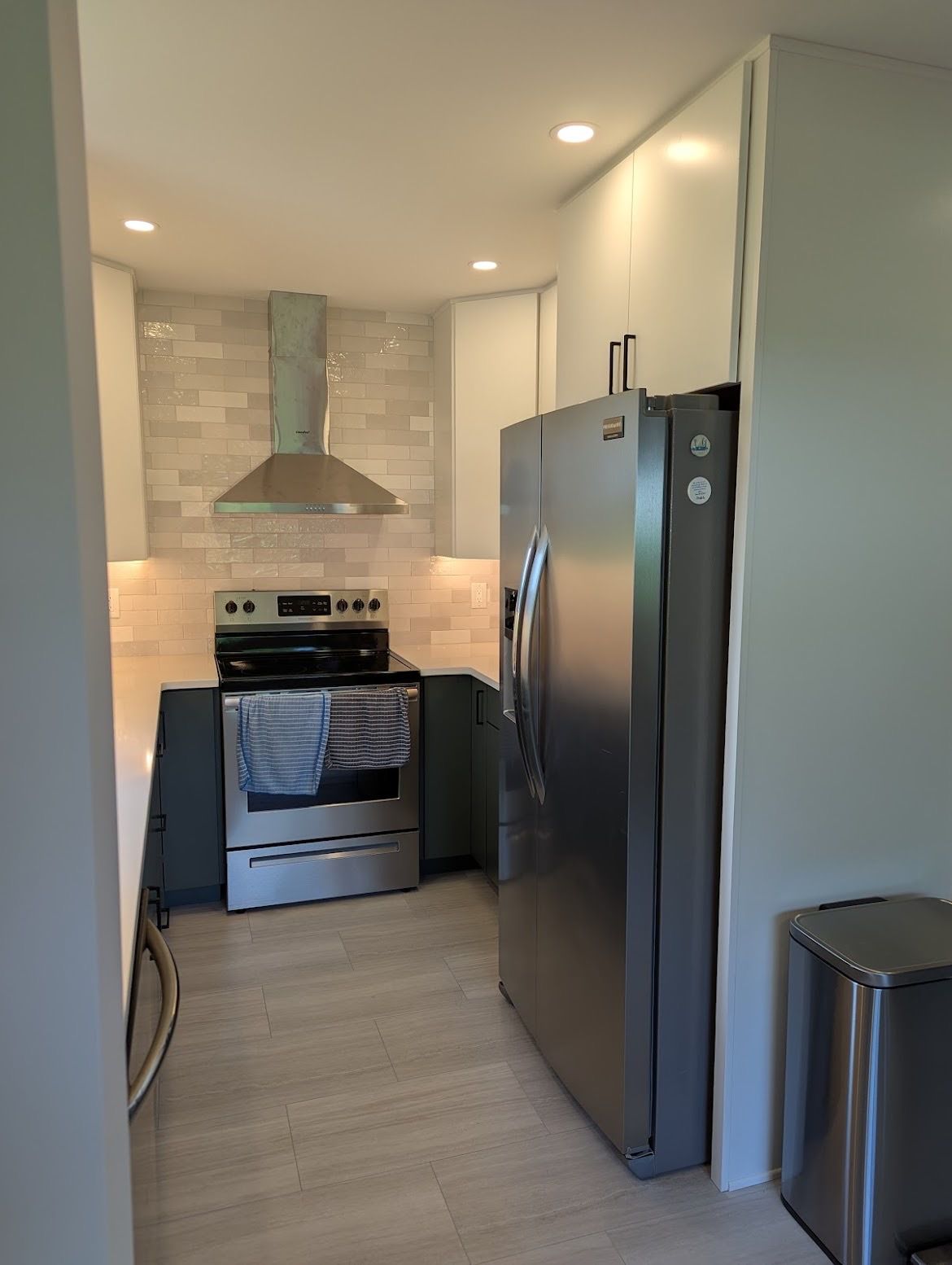 A kitchen with a stove , refrigerator , and trash can.
