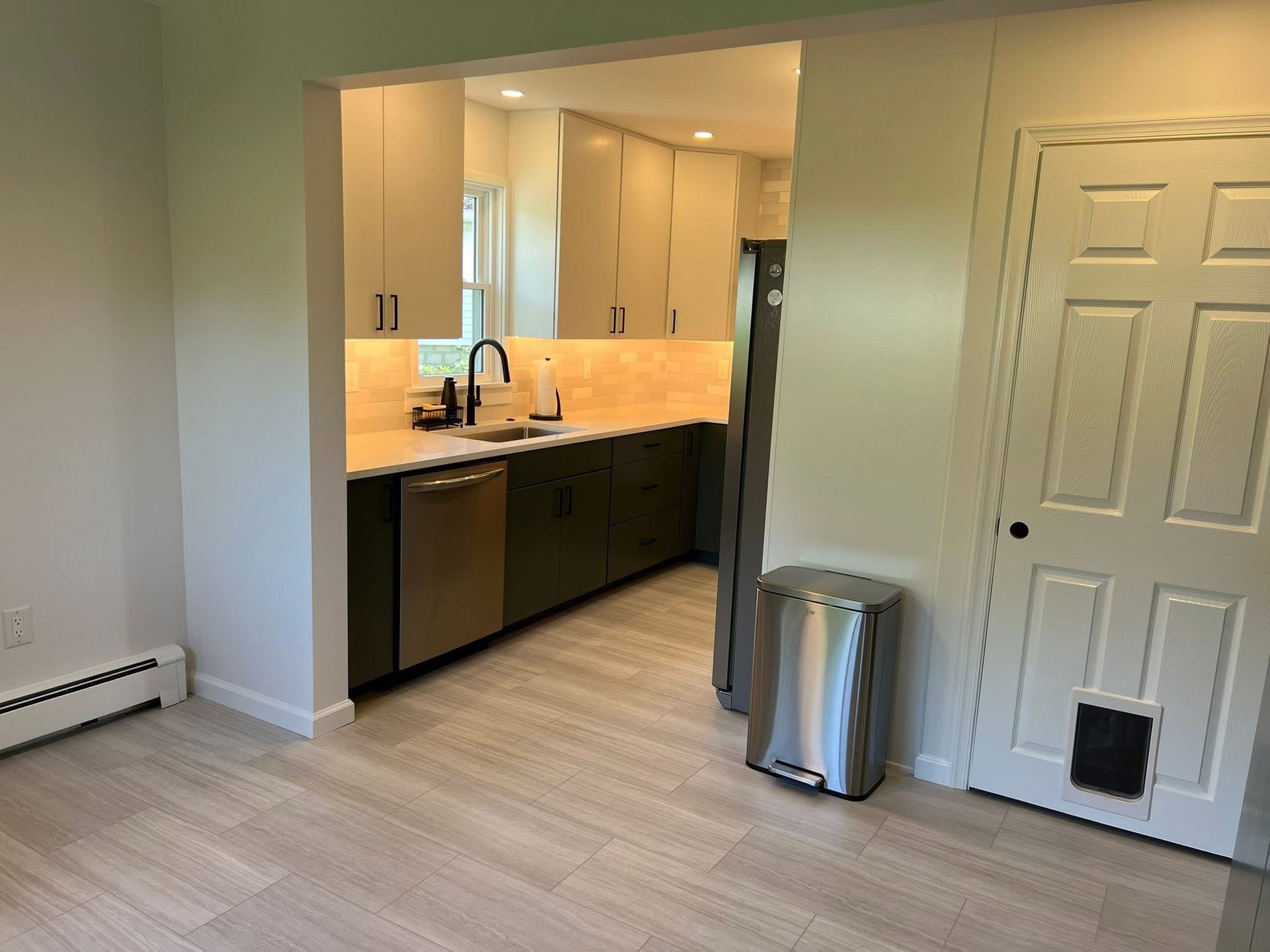 A kitchen with stainless steel appliances and a cat door.