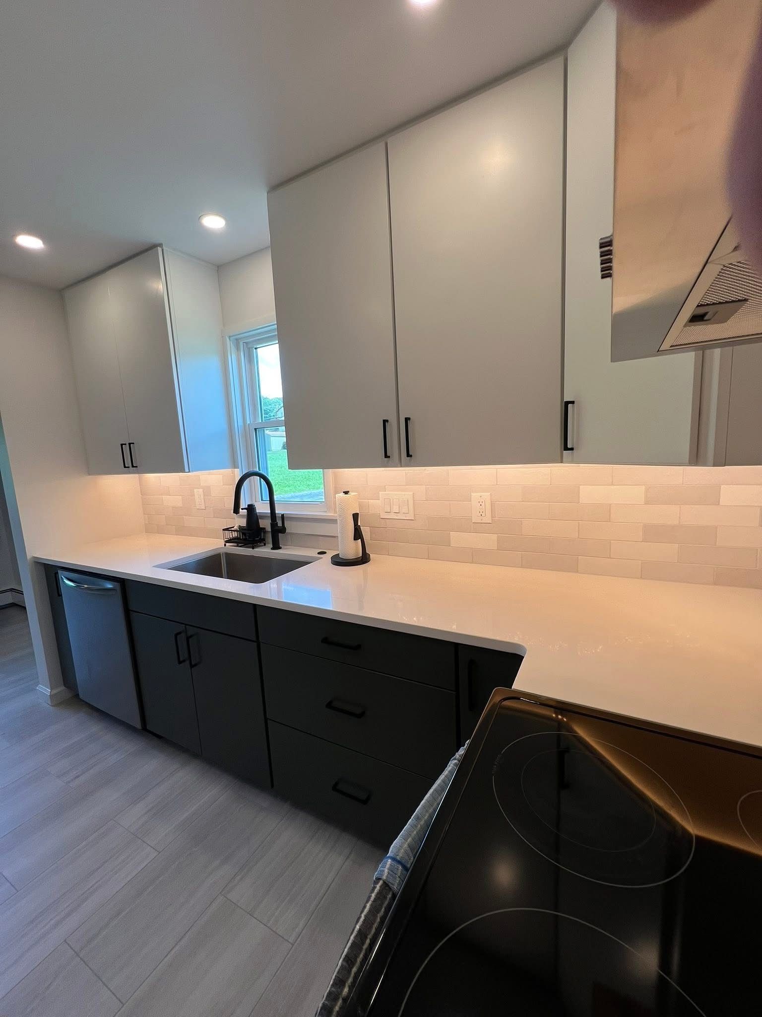 A kitchen with a sink , dishwasher , and stove top oven.