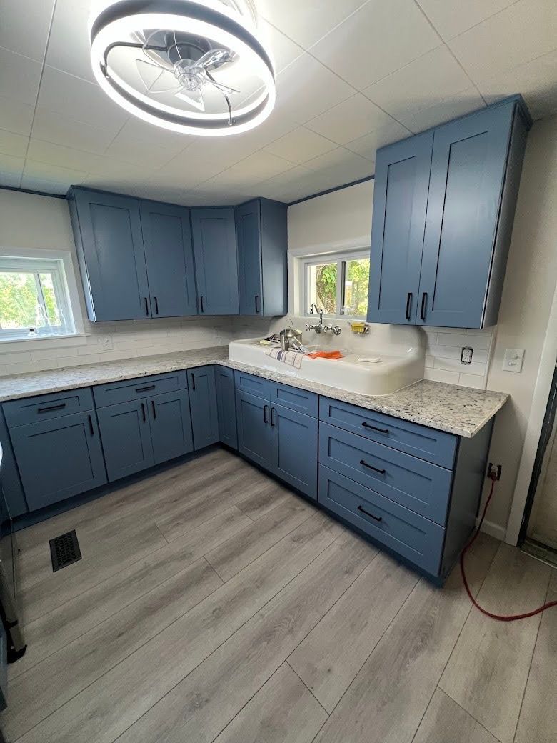 A kitchen with blue cabinets , granite counter tops , and a sink.
