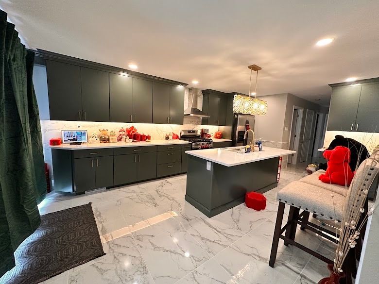 A kitchen with green cabinets , white counter tops , and a large island.