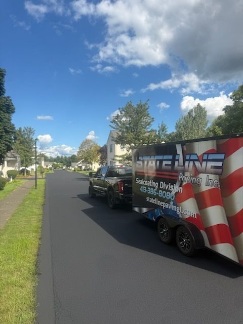 Truck with red, white, and blue graphics parked on a sunny residential street under a blue sky