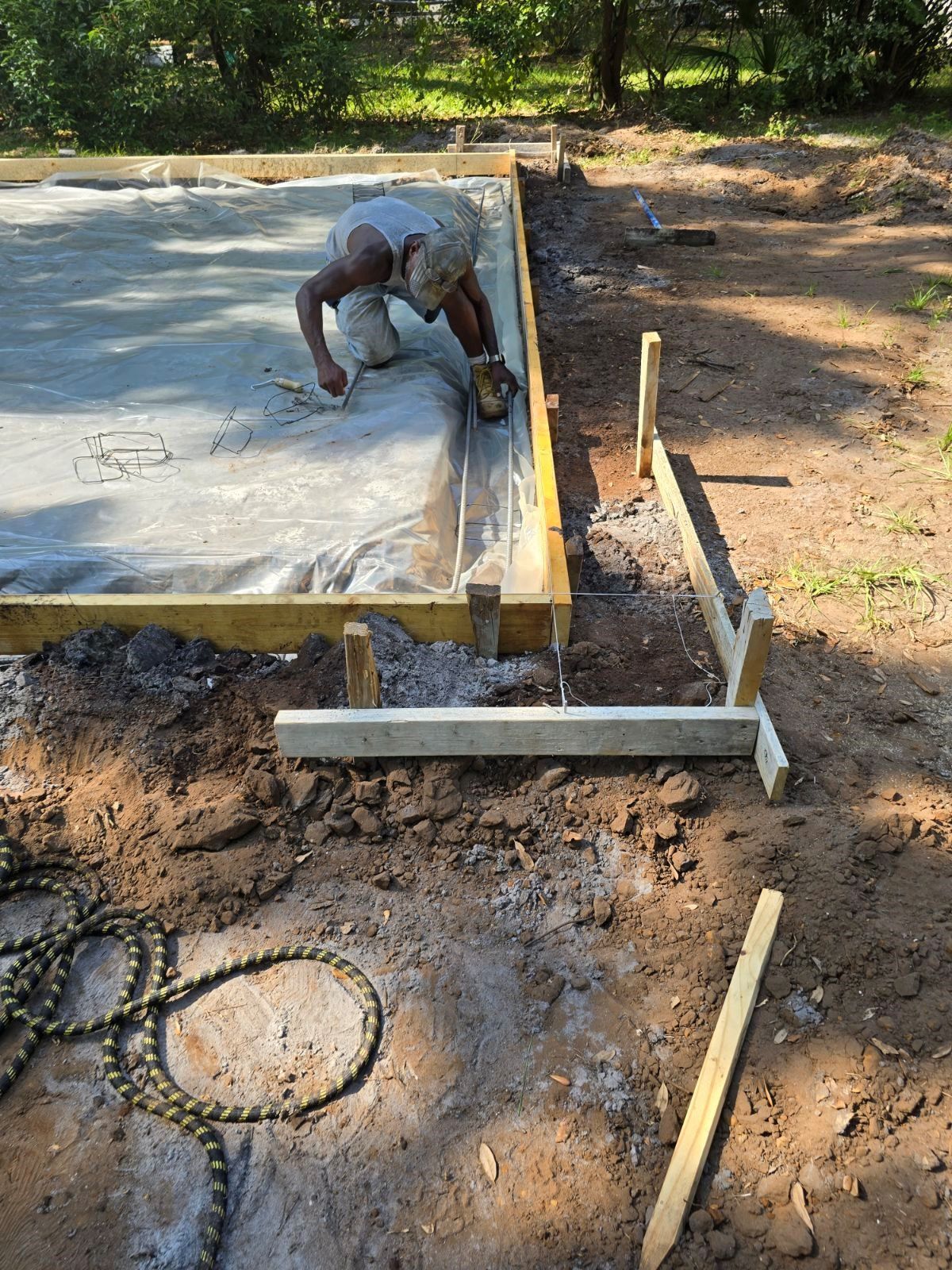 A man is working on a concrete slab in the dirt.